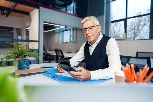 Mature man working on architectural project in office