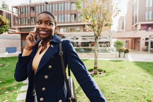 Female african student talking on the phone near the university campus