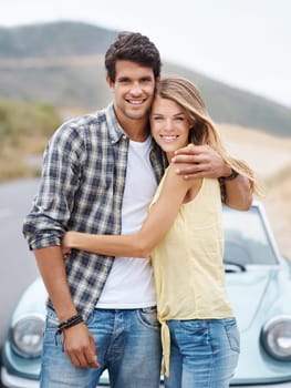 Carefree youth. A romantic young couple standing alongside their convertible while on a roadtrip.