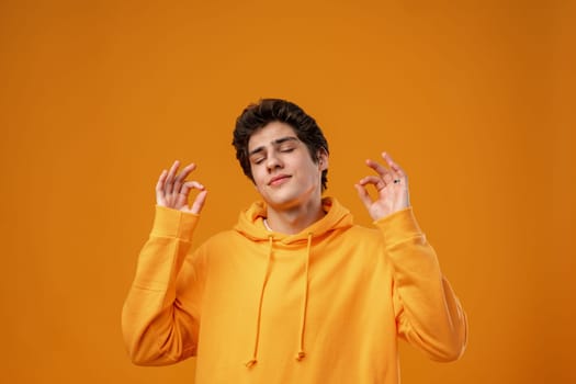 Young handsome man over yellow background with eyes closed doing meditation gesture with fingers