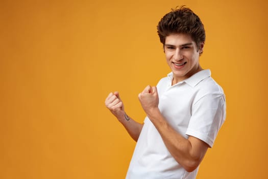 Portrait of a satisfied young man celebrating success over yellow background