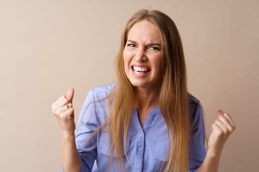 Angry stressed mad young woman against beige background
