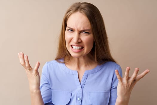 Angry stressed mad young woman against beige background