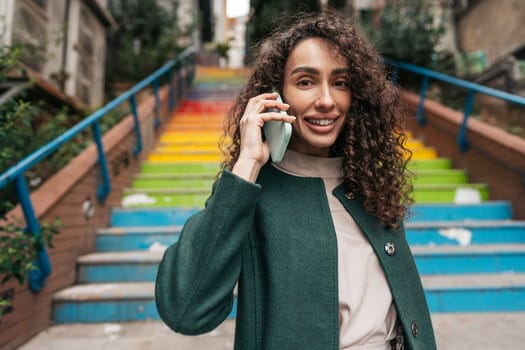 Young attractive woman stands near the rainbow stairs in Istanbul and using a phone