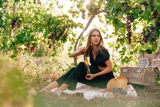 Young blonde woman sitting on a picnic in a vineyard