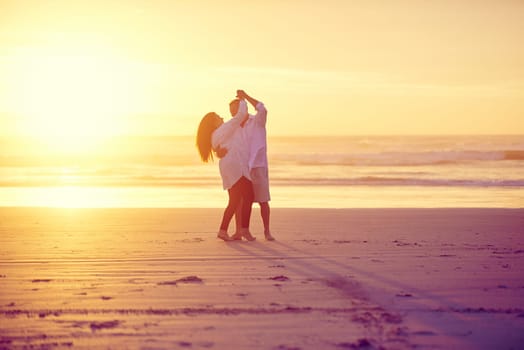 Sun-kissed lovers. Full length shot of an affectionate mature couple dancing on the beach at sunset.