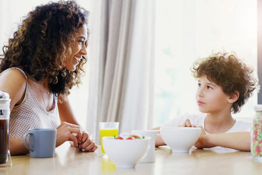 Family, breakfast and kid with mother at morning in a home with happiness and orange juice with care. Mom, food and young child together with love and support with healthy drink and youth with smile.