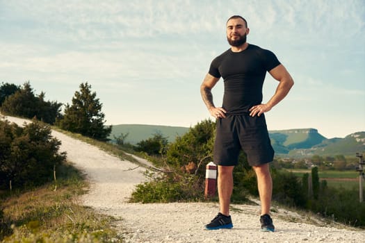 Sporty man standing on hill in the countryside
