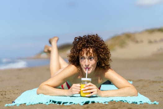 Happy woman with cool drink on beach