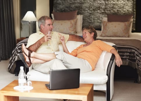 Retirement, love and an old couple drinking wine in their hotel room while on holiday or vacation together. Toast, sofa or relax with a senior man and woman bonding at a luxury resort for romance.