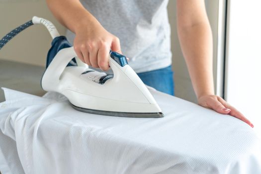 Woman ironing white shirt on ironing board