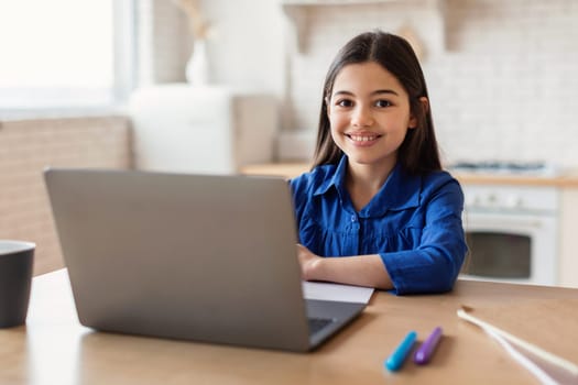 Enthusiastic Schoolgirl Engages in Online Studies Using Laptop At Home
