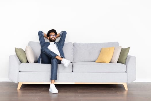 Relaxed happy young eastern guy chilling on couch at home