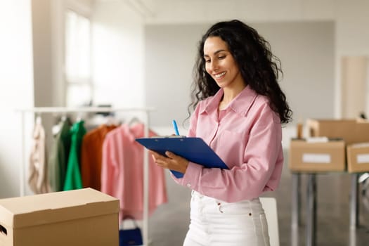 Confident Businesswoman Organizing And Packing Clothes Orders In Stylish Showroom