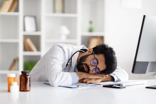 Tired overworked middle eastern doctor sleeping at working place
