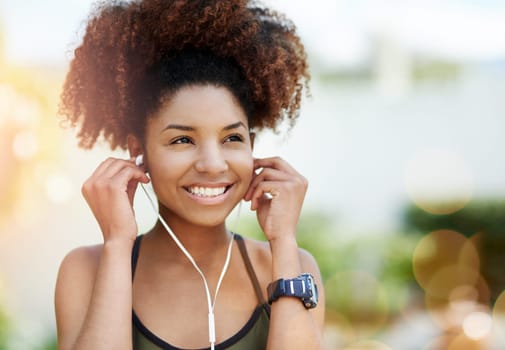 Music is my number one inspiration. Cropped shot of a young woman inserting her earphones before a run.