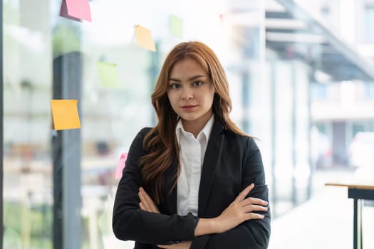 Portrait young confident Asian business woman leader, successful entrepreneur, elegant professional company executive ceo manager, wearing suit standing in office with arms crossed in meeting room