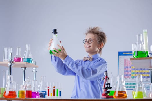 Funny smiling boy holding flask with reagent