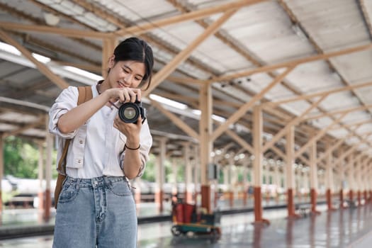 portrait of a young woman traveler with small backpack and camera on the railway stantion