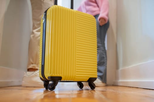 Closeup Of Yellow Suitcase While Tourists Couple Entering Hotel Room