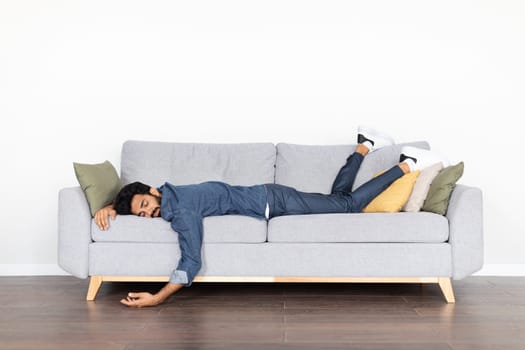 Exhausted eastern man sleeping on couch at home
