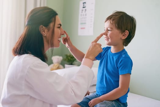 Woman doctor, playing and child fun at a hospital for healthcare and medical consultation. Smile, trust and pediatrician touch nose with a laugh and happiness in a clinic with boy patient with exam