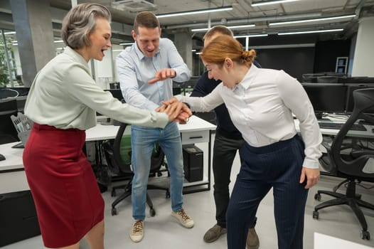 Four colleagues give the low five in the office.