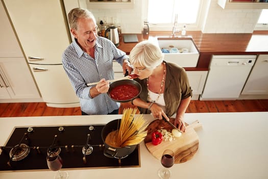 Top view, taste or old couple kitchen cooking with healthy food for lunch or dinner together at home. Love, help or senior woman tasting or eating with mature man in meal preparation in retirement