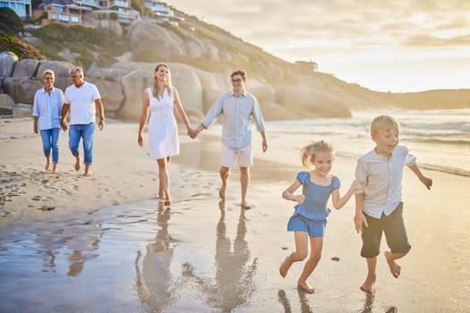 Family, generations and kids with running, beach and sunset with men, women and happiness with love. Parents, grandparents and children by ocean, holding hands or bond on summer vacation with smile