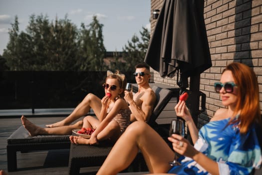 A happy family in swimsuits sunbathe in summer on their terrace on sun beds