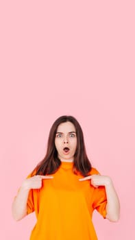 Young Woman Pointing at Herself in Amazement, Expressing Belief in Winning the Competition. Positive Image of Self-Assurance and Determination. Isolated on Pink Background for Impactful Visuals.