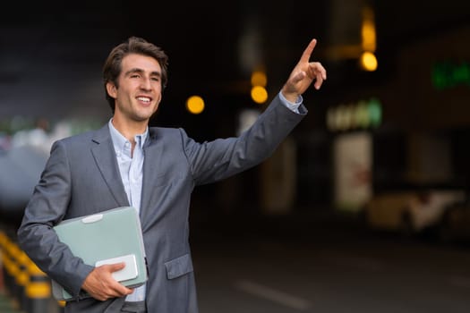 Happy young businessman catching taxi on the street