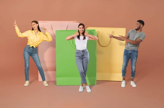 Concumerism concept. Positive beautiful multiethnic millennial people man and women in casual posing by big shopping bags over colorful background, collage. Shopaholics enjoying black friday sale