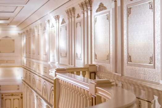 The interior of the event hall in a classic style with stucco on the walls and marble railings
