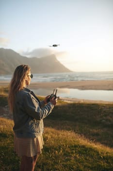 Drones capture the best footage of the scenery. an attractive young woman flying a drone outdoors.