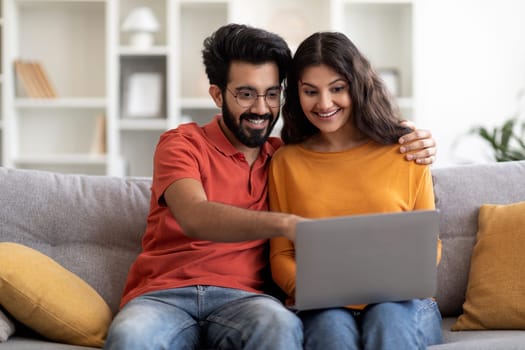 Young Indian Couple With Laptop Booking Vacation Online While Relaxing At Home