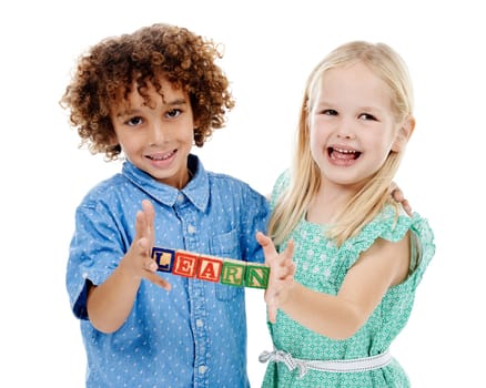 We made this together. Studio shot of a cute little boy and girl holding building blocks that spell the world learn against a white background.