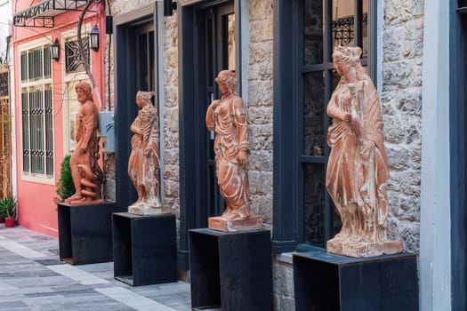Nafplion, Greece - July 12 2021: Ancient Greek full-size statue replicas outside a shop facade.