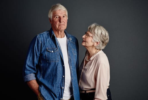 Keeping his naughty side in check. Studio portrait of an affectionate senior couple posing against a grey background.