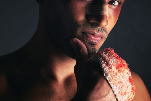 Fight, blood and portrait of man with bruise on eye, face and bloody bandages on hand. Violence, boxing and young male boxer with injury, wounds and hurt from mma sport on black background in studio