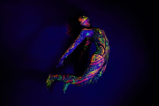 Woman, neon paint and dancer jump on dark background for creative performance, splatter texture and psychedelic fantasy. Body artist, color splash and unique glow in surreal circus on mockup studio.