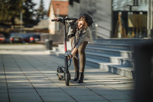 A young businesswoman going to work with an electric push scooter.
