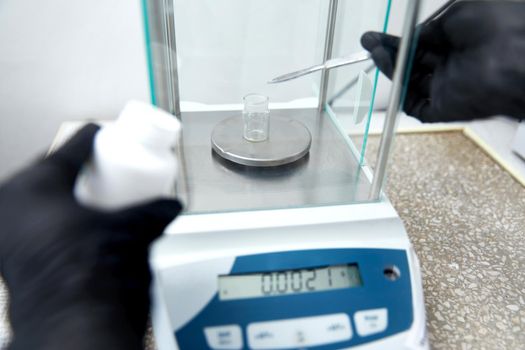 Scientist weighing chemicals by digital scales in grams in chemical laboratory