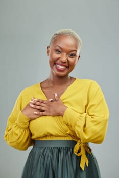 Portrait, thank you and hands on chest of happy woman in studio with love sign on wall background. Face, smile and hand on heart by female person showing gratitude, kindness and self care or honesty