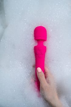Woman lies in a bubble bath and uses a vibrator.