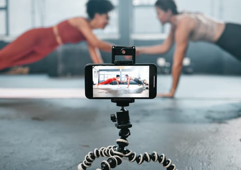 Influencer, phone and fitness people recording, filming or broadcast online training video, exercise tutorial or guide. Sports, handshake and athlete team, women of friends live streaming gym workout.