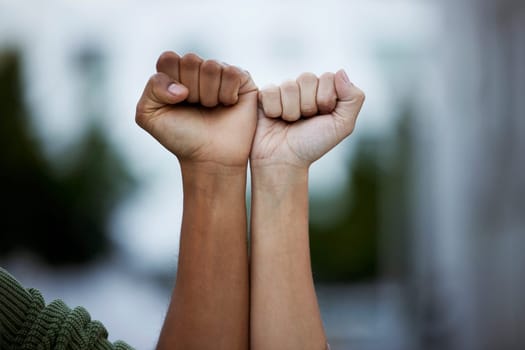 Fist, protest and power by people in solidarity for justice, human rights and democracy on blurred background. Hands, diversity and men united for activism, change and transformation or community