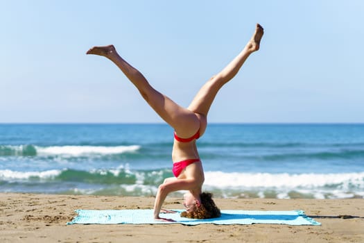 Healthy woman doing yoga on sandy coast
