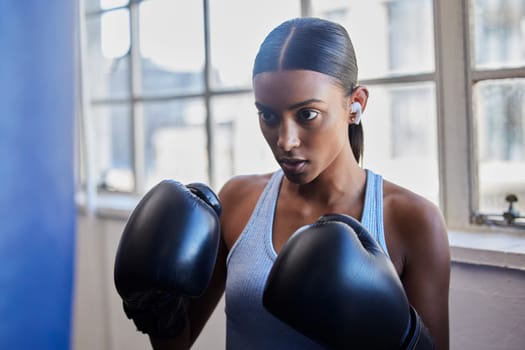 Boxing, fitness and Indian woman in gym for training, exercise and kickboxing lesson. Sports, wellness and female athlete with boxing gloves for focus, determination and motivation for strong muscles