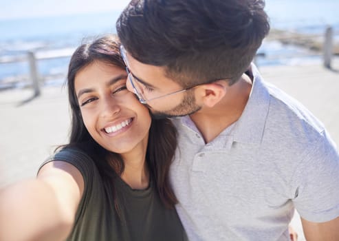 Couple, love and selfie at the beach, travel and kiss by ocean with support, trust and care with adventure in Mumbai. Smile in picture, happy and memory with smartphone photography for romance.